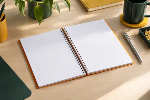 Bloc-notes orange A4 à spirale ouvert sur des feuilles quadrillées de petits carreaux violets
